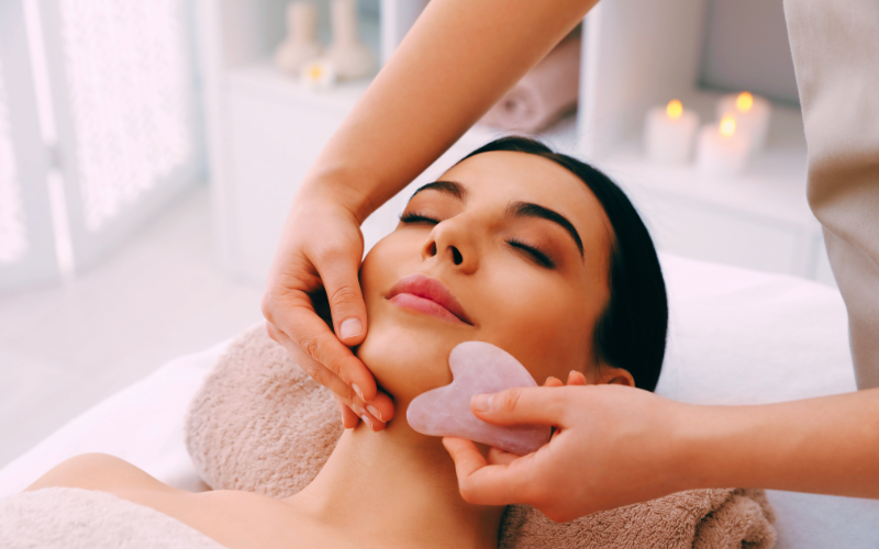 A woman receiving a relaxing rose quartz Gua Sha facial massage from Lumi Glow’s home delivery service in Bangkok.
